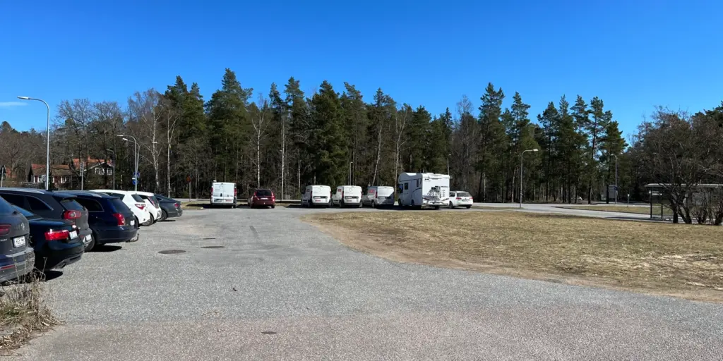 Grusplan med parkerade bilar.