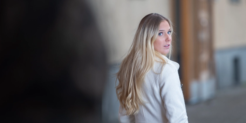 En kvinna går längs en gata och vänder sig om mot en skugga.