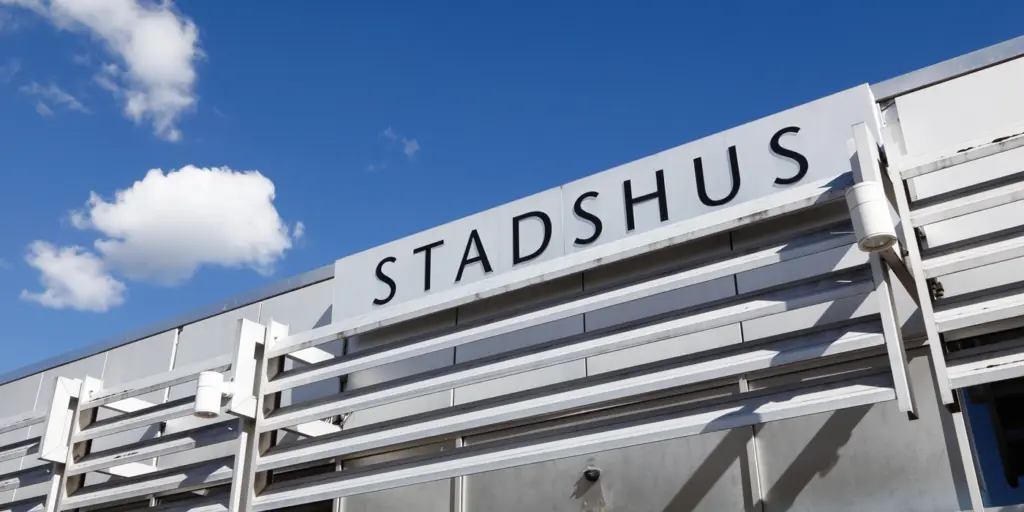 En närbild på en skylt på ett stadshus med himlen i bakgrunden.