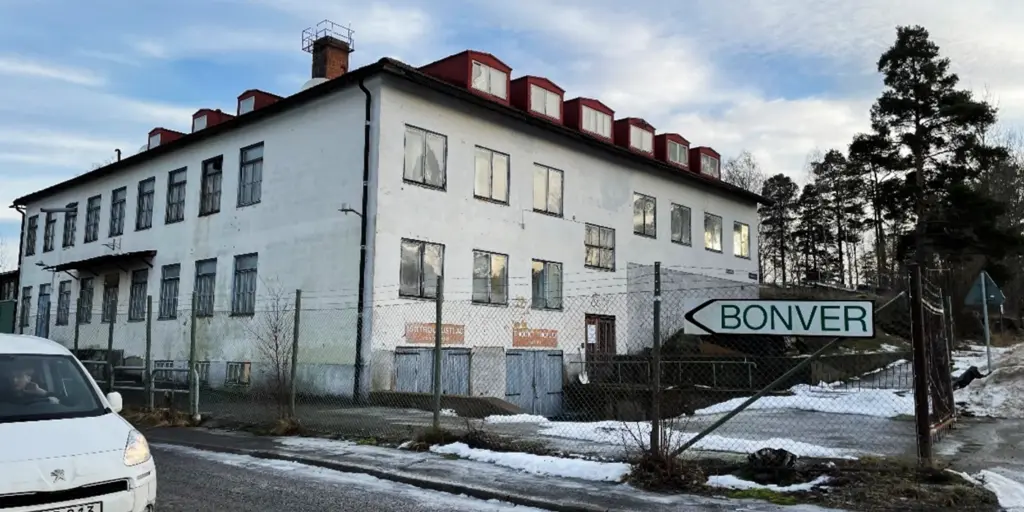 Vit större byggnad bakom stängsel.