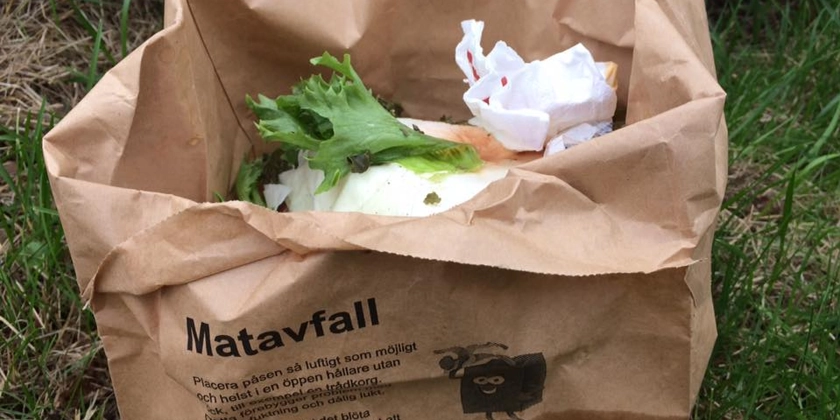 En matavfallspåse fylld med matrester på en gräsmatta.