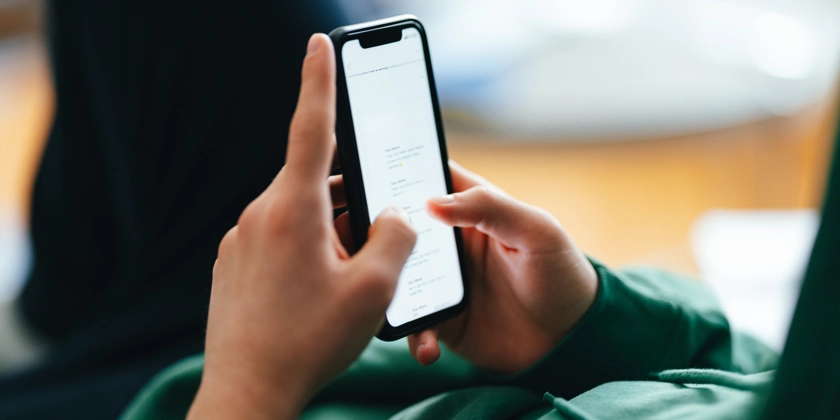 En närbild på en ung persons händer som håller i en mobiltelefon.