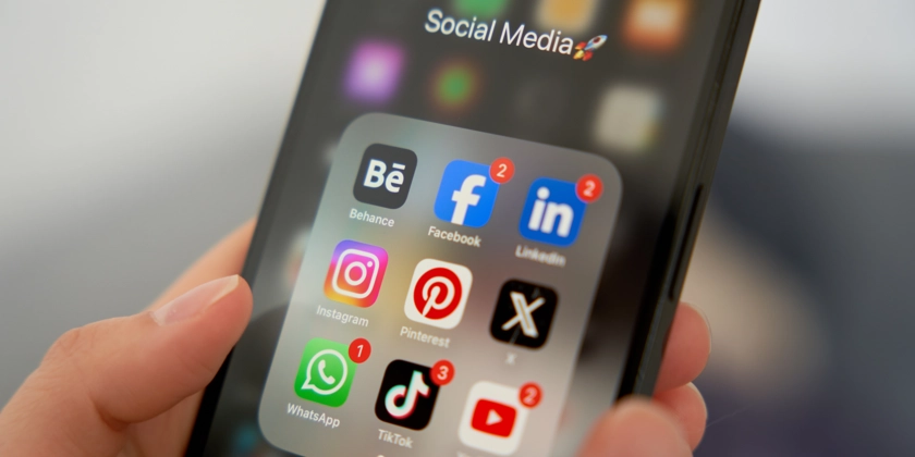 En person som håller i en smart telefon med ikoner för sociala medier.