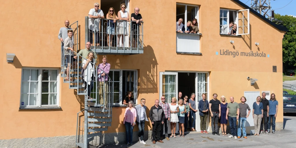 Gruppfoto av personal vid Lidingö musikskola taget vid fasaden.