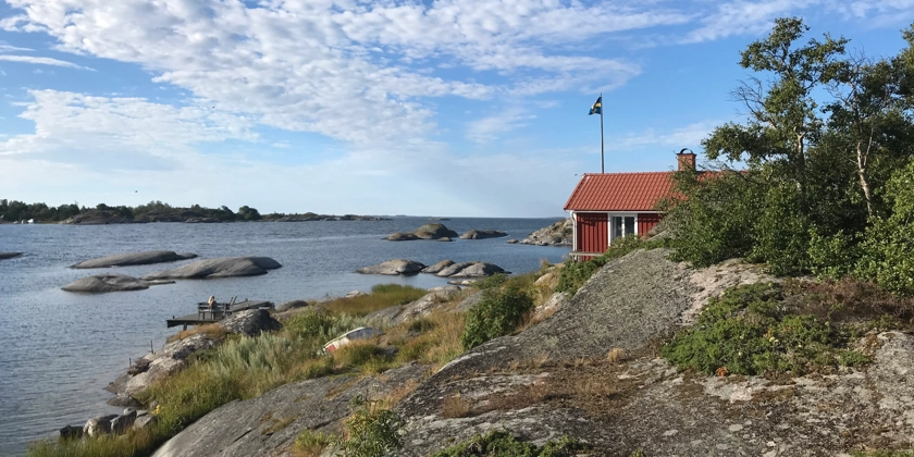 Ett rött hus på en klippa vid havet.