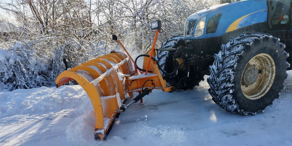 En traktor plogar snö på liten gata
