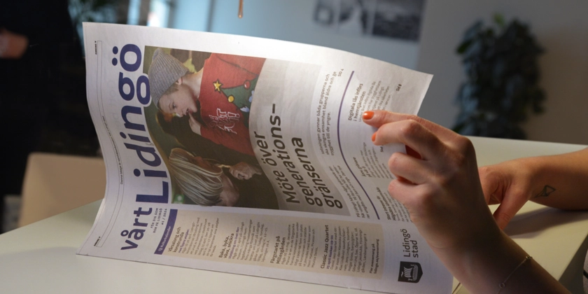 En kvinna sitter vid ett bord och läser en tidning.