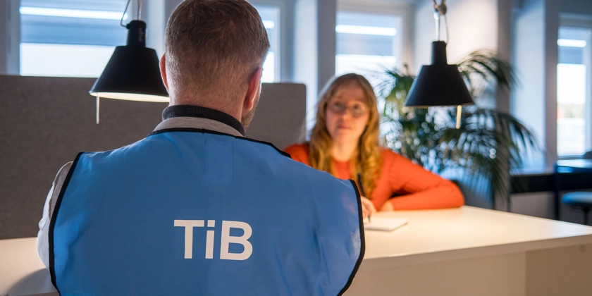 En man med TiB-väst och en kvinna bakom ett bord.