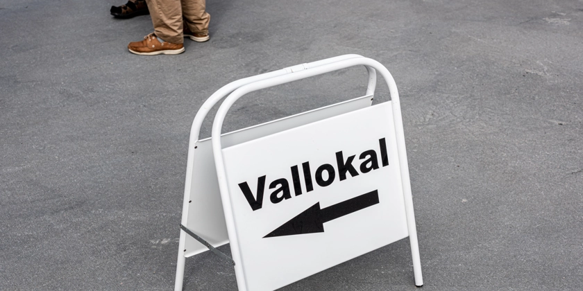 En vit skylt med texten vallokal och en pil som pekar åt vänster.