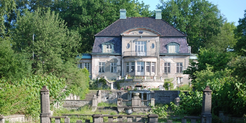 En stor stenvilla med trädgård.