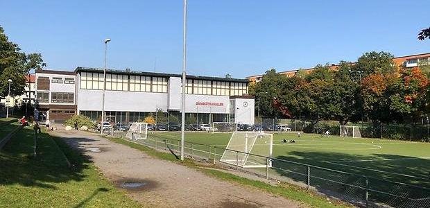 Gångsätrahallen med fotbollsplan och gångväg i förgrunden.