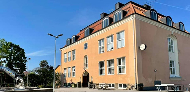 Bild på skolbyggnaden med klätterställning i förgrunden
