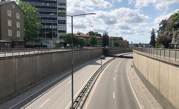 Större väg i ett betongtråg med hus vid sidan