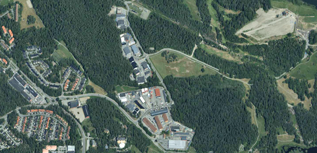 Flygbild över ett området med byggnader och skog runtomkring.