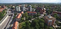Drönarbild över stor väg med två broar, flerbostadshus vid sidan om vägen.