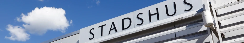 En närbild på en skylt på ett stadshus med himlen i bakgrunden.