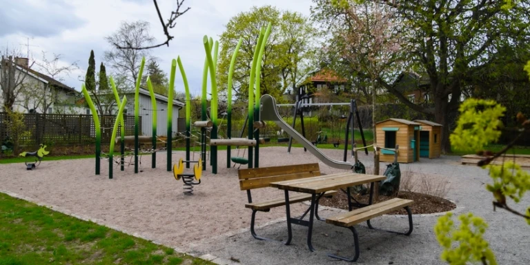 En lekpark med olika lekställningar samt ett picknickbord.