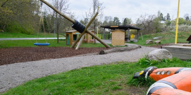En lekpark med en giraffgunga med kompisgunga.