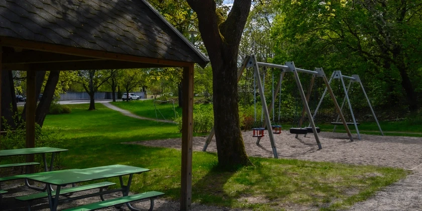 Gungställningar och picknickbord omgiven av grönska.