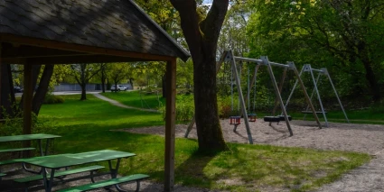 Gungställningar och picknickbord omgiven av grönska.