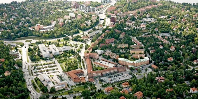 Flygfoto över en stadsdel med vatten och en bro i bakgrunden.