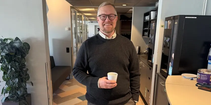 Porträttbild av Daniel Ek som står med en kaffekopp och ler glatt in i kameran