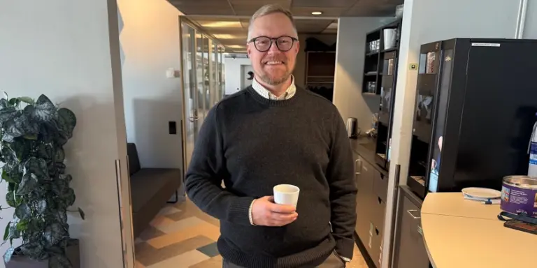 Porträttbild av Daniel Ek som står med en kaffekopp och ler glatt in i kameran