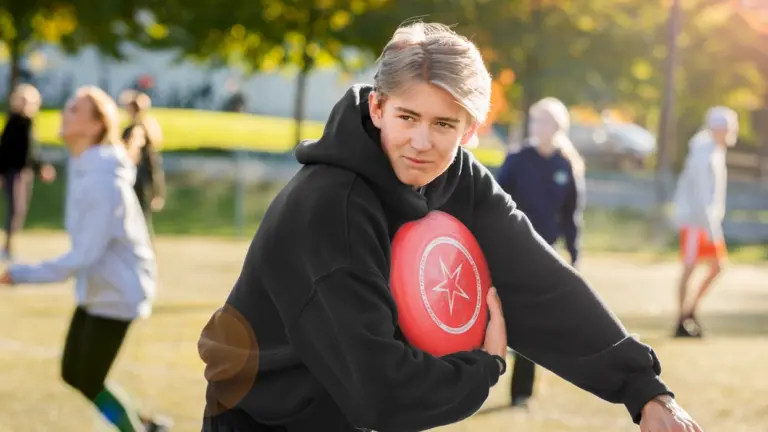 En ung man ska kasta en röd frisbee.