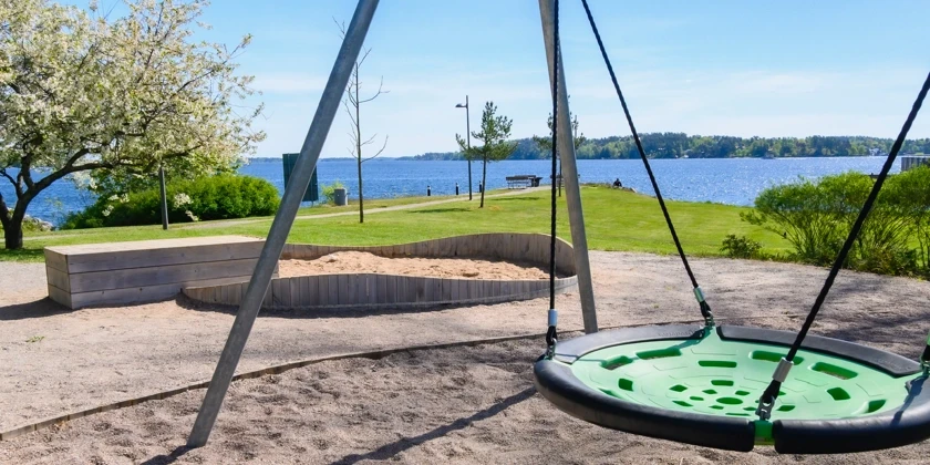 En lekpark med en kompisgunga nära havet.