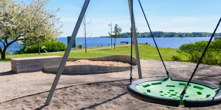 En lekpark med en kompisgunga nära havet.