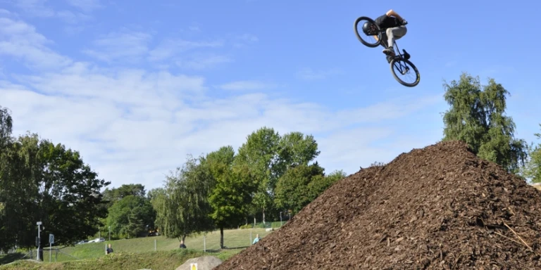 En ung man hoppar med sin BMX i en bikepark.
