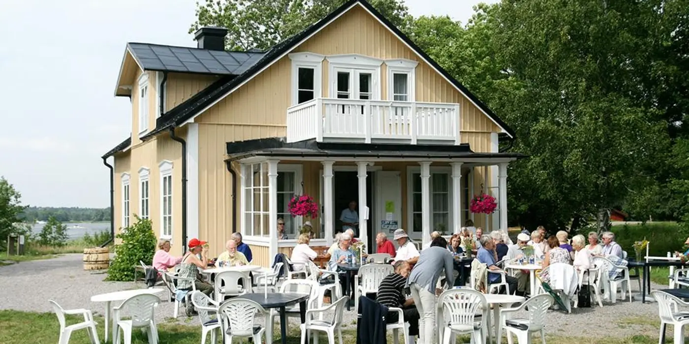 Gäster på en uteservering vid en gul villa.