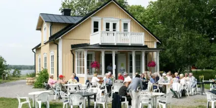 Gäster på en uteservering vid en gul villa.