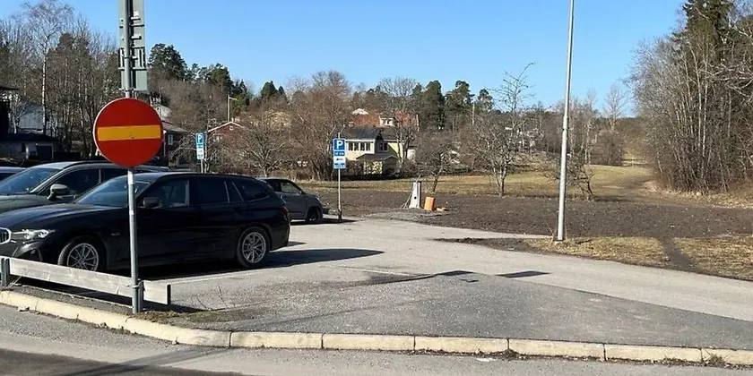 Parkeringsplats med svart bil närmast kameran och förbjuden infartsskylt i förgrunden