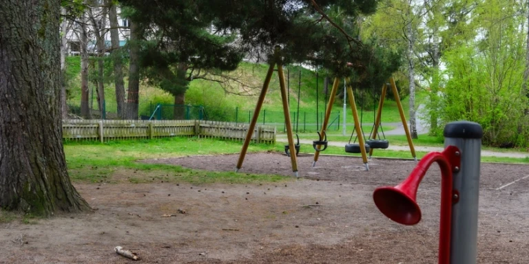En gungställning i en lekpark bredvid ett träd.