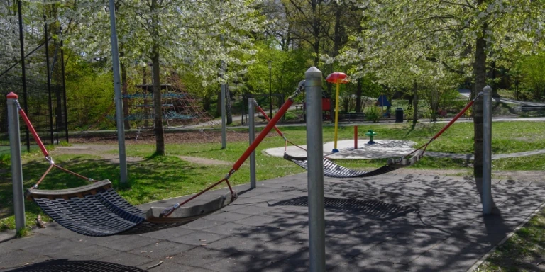 En lekpark med hängmattor omgiven av grönska.