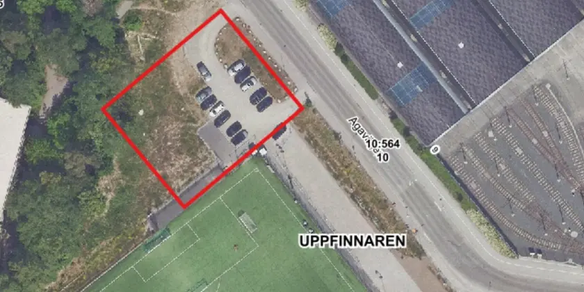Flygfoto visar parkeringsplatsen bredvid den gröna fotbollsplanen och är markerad med en röd kvadrat som visar var arbetet ska pågå. 