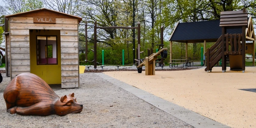 En lekpark med en träskulptur av en sovande björn. 