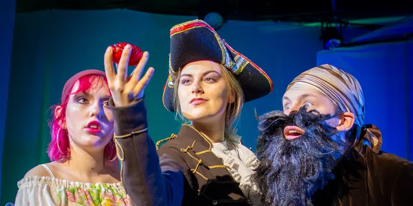 En ensemble på en scen i piratkostymer.