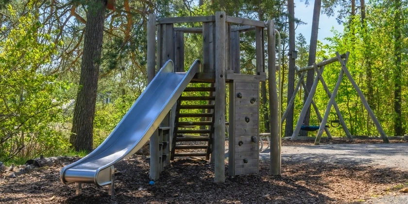 En naturlekpark med gungställning och klätterställning med rutschkana.