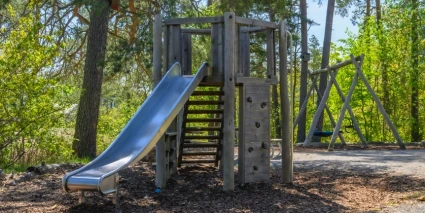 En naturlekpark med gungställning och klätterställning med rutschkana.