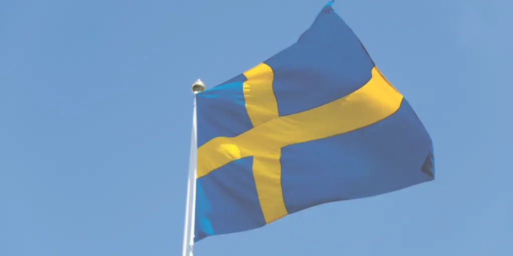 En svensk flagga som vajar mot en klarblå himmel.