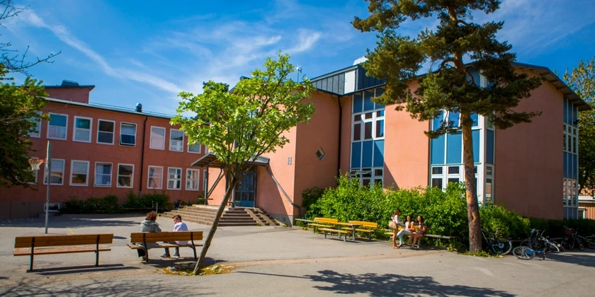 Elever sitter på bänkar på skolgården.