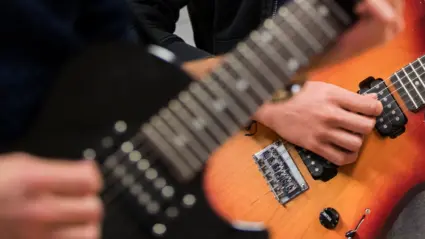 Två personer spelar elgitarr.