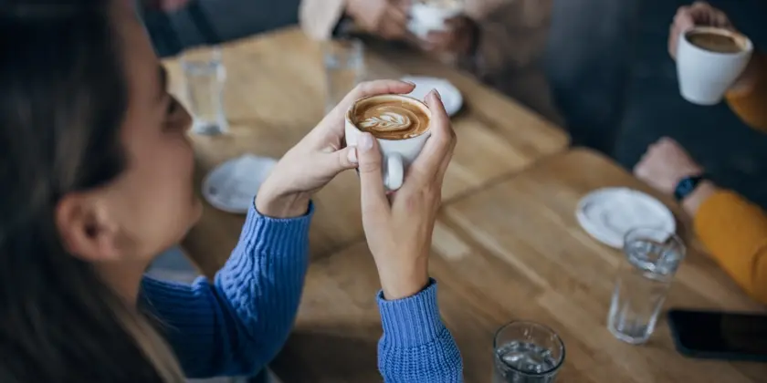 Kvinna i blå tröja sitter med en kaffekopp i handen