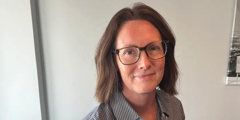 Porträtt av Lena Wennerklint sittandes vid ett bord. 