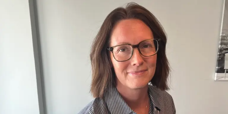 Porträtt av Lena Wennerklint sittandes vid ett bord. 