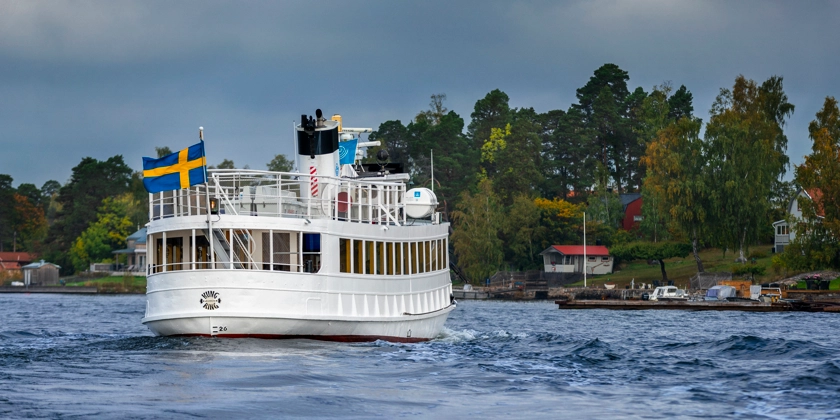 En skärgårdsbåt med svenska flaggan har lämnat en brygga.