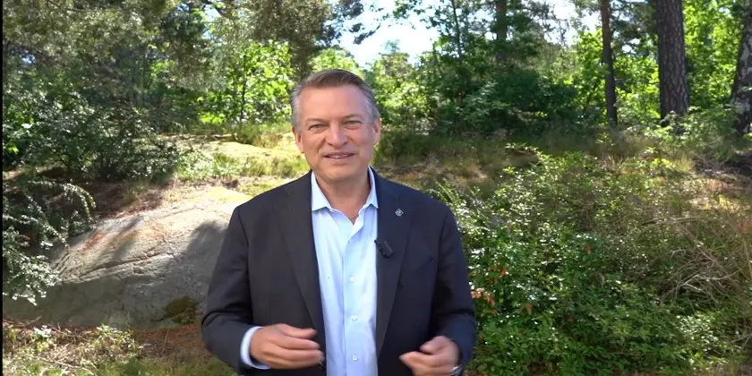 Stadsdirektören står i en skog och är klädd i kostym.