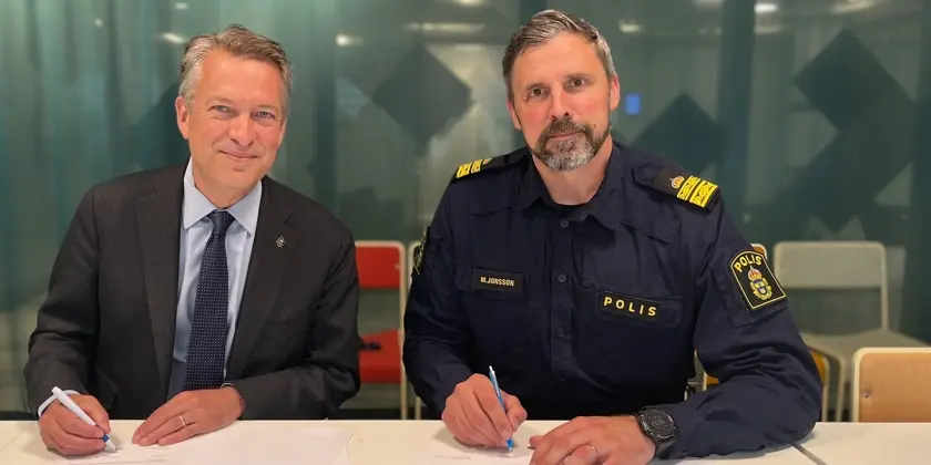 Stadsdirektör och polisman sitter vid ett bord och skriver under samverkansavtal.
